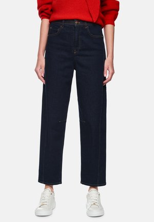 Dark denim high-waisted jeans with a straight leg, featuring front and back pockets, and contrast stitching. Paired with white sneakers.