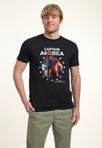 Camiseta negra de algodón con un gráfico circular del Capitán América, con estrellas y texto. Cuello redondo y mangas cortas, de textura suave.