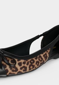 Ballerine noire avec côtés imprimés léopard et petit nœud sur l’avant, ouverte au talon avec une fermeture par bride.