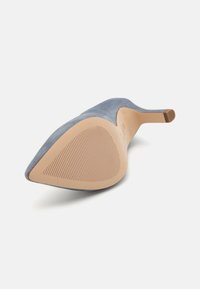 Pumps blu scamosciato con punta affusolata e tacco sottile, dotate di una suola beige testurizzata. Presentano una silhouette elegante e una finitura superiore liscia.