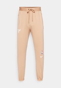 Bež športne hlače iz mehkega blaga, ki imajo elastični pas z vrvico, stranske žepke in logotipe Nike in Chicago Bulls.