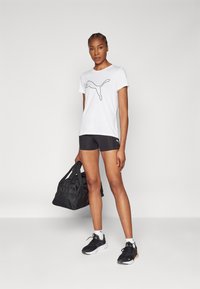 Valge särk musta Puma logoga, koos mustade spordilühikestega. Must reisikott ja mustad spordijalatsid täiendavad komplekti.