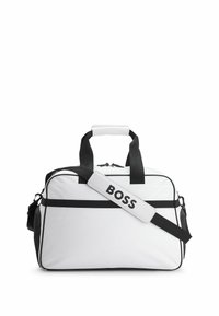 Duffle taske i hvidt stof med sorte detaljer, der har dobbelte håndtag, en justerbar rem og et logo-patch på remmen.