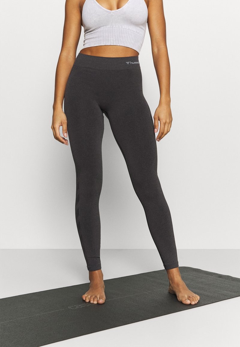 Leggings gris ajustés avec une texture lisse et une taille haute, présentant un logo discret sur la taille et sans motifs ou accents visibles.