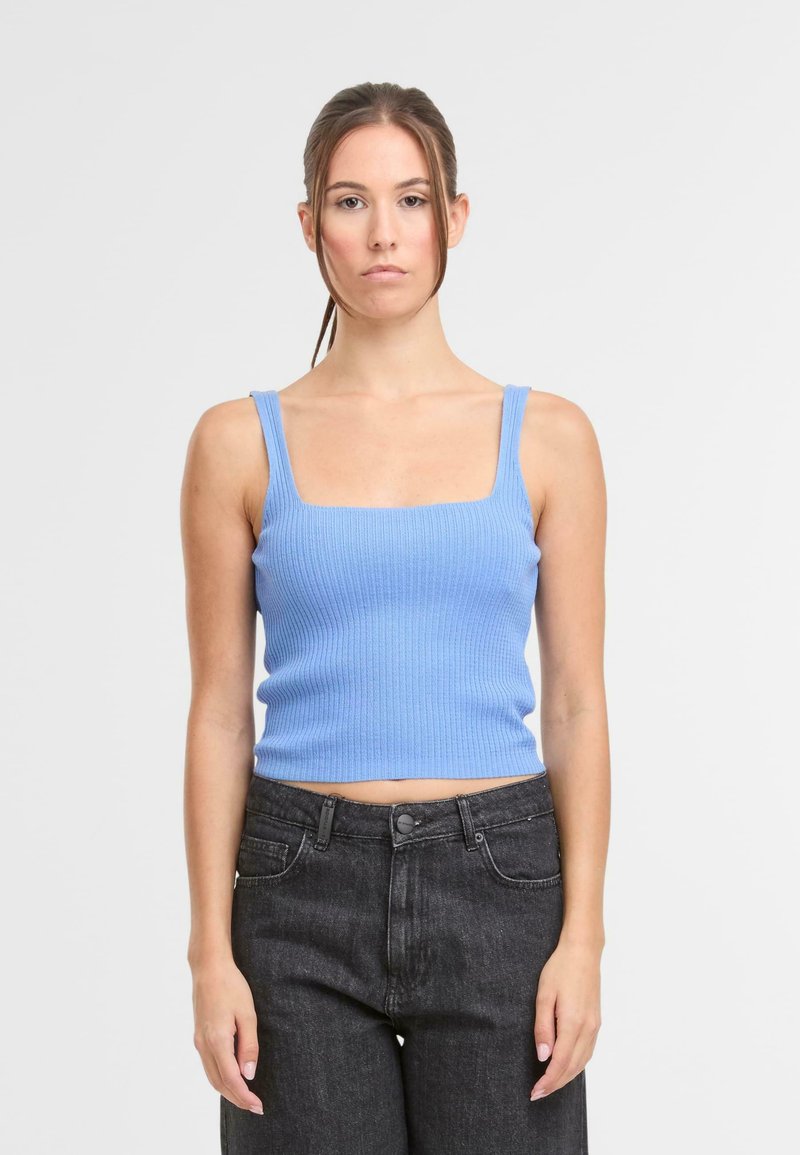 Lichtblauwe, geribbelde crop top met een vierkante halslijn en brede schouderbanden, gecombineerd met hoge taille donkere jeans.