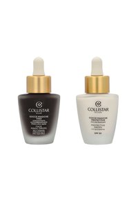 Two glass dropper bottles side by side. Left: dark brown with a gold cap, labeled "Face Magic Drops." Right: white with a gold cap, labeled "Protective Drops SPF 50."
