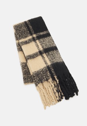 Écharpe en laine douce avec motif à grands carreaux noirs et beiges et extrémités à franges, pliée sur fond blanc.