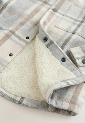 Károvaná flanelová košele s bundou s vlnenným povrchom v mäkkej šedej a béžovej farbe, podšitá krémovým umelým ovčím kožúškom. Obsahuje kovové cvoky.