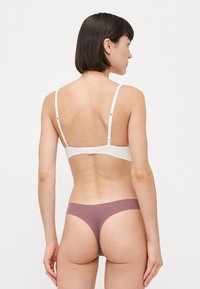 Witte bralette met verstelbare bandjes en een haak-en-oogsluiting, gecombineerd met mauve laag uitgesneden thong. Gladde stof met een minimaal ontwerp.
