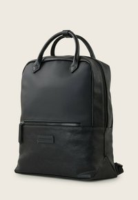 Czarny skórzany plecak z gładkim materiałem na górze, kieszenią na zamek i podwójnymi uchwytami do noszenia. Kompaktowy prostokątny kształt.