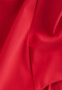 Tissu rouge lisse avec des plis doux et une légère brillance, mettant en valeur sa texture et son tombé.