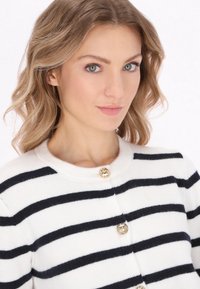 White and navy striped cardigan featuring a round neckline, gold button fastenings, and soft texture. Snug fit, classic design.