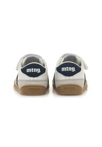 Sneaker bianche con un accento blu navy, dotate di una fascetta in Velcro, materiali in camoscio e pelle, e suola in gomma testurizzata. Nome del marchio visibile.