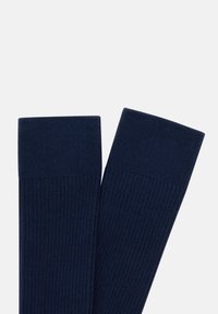 Marina-blå ribbade strumpor med en stickad textur och breda muddar, med en sömlös design för komfort och en klassisk passform.