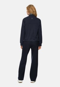 Navy blue sweatshirt and pants set made from soft fabric. Features ribbed cuffs and a relaxed fit, with a clean back design.