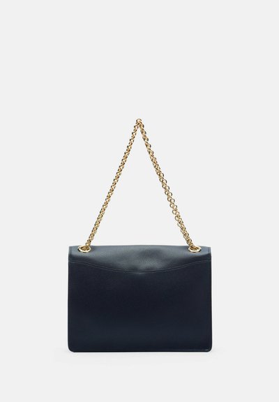 Sac à main en cuir noir avec une bandoulière en chaîne dorée, de forme rectangulaire et une surface texturée sur un fond clair uni.