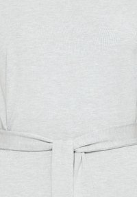 Tissu gris clair avec une ceinture nouée autour de la taille, créant un nœud simple au centre.
