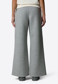 Harmaat väljät collegehousut, jotka on valmistettu pehmeästä kankaasta. Niissä on sileä rakenne, löysä istuvuus ja puhdas, yksinkertainen muotoilu ilman näkyviä kuvioita.