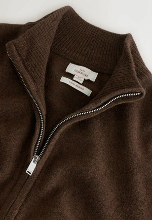 Brązowy sweter zapinany na zamek, wykonany w 100% z wełny merynosów, z prążkowanym kołnierzem i suwakiem w srebrnym odcieniu, z widocznymi metkami marki wewnątrz.