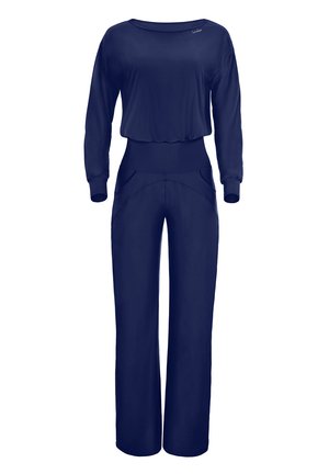 Marinblå långärmad jumpsuit i mjukt tyg, med smal midja, vida byxben och diskreta fickdetaljer fram.