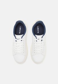 White Levi's sneakers with a smooth leather exterior, navy textile lining, white laces, and subtle branding on the tongue and side.