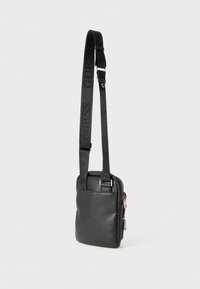 Schwarze Leder-Crossbody-Tasche mit strukturiertem Finish, verstellbarem Tragegurt mit Logo-Details und Reißverschluss.
