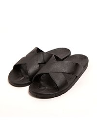 Chanclas negras con correas sintéticas cruzadas, plantilla texturizada y suela de goma plana, que presentan un diseño simple y funcional.
