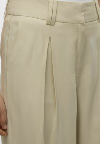 Beige kalhoty na míru s hladkým povrchem, předními záševky, rovným střihem a standartním pasem.