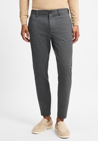 Grijze geplaid broek gemaakt van textuurstof, met een vlakke voorkant, riemlussen en taps toelopende benen. Gecombineerd met beige instappers.