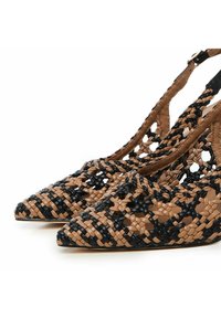 Scarpe con tacco slingback intrecciate che presentano un mix di materiali in tonalità marrone e nera, punte affusolate e un design aperto e strutturato.