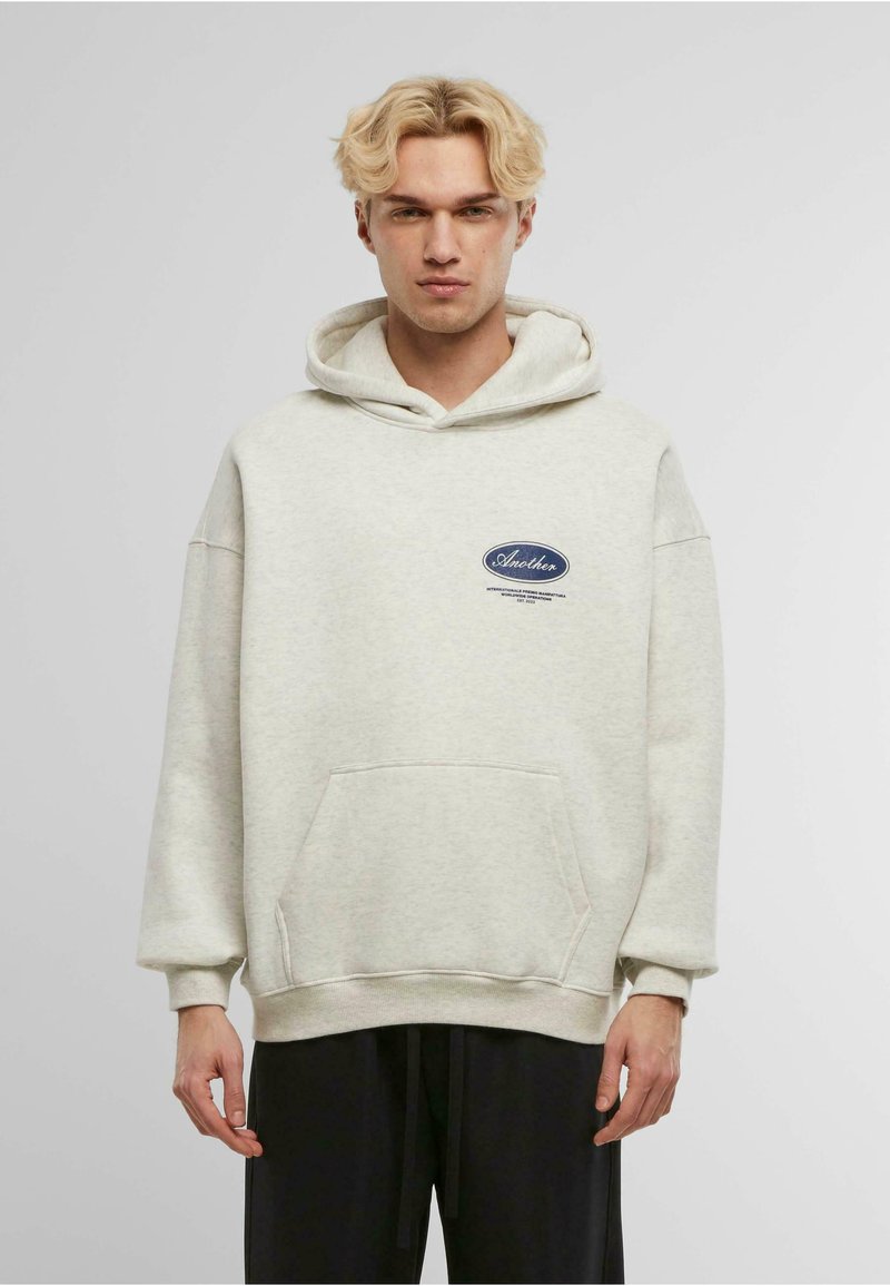 Hoodie grigio chiaro realizzato in misto cotone, con tasca a marsupio frontale, cappuccio con cordini e patch con logo sul petto. Vestibilità rilassata.