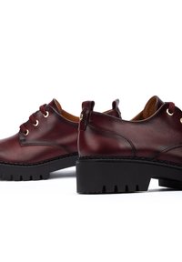 Chaussures en cuir bordeaux à finition lisse, à lacets, avec œillets dorés et semelles en caoutchouc noir texturé pour une adhérence et une durabilité.