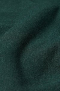 Dunkelgrüner Stoff mit einer weichen Textur; eng gewebt mit leichten Farbvariationen, die eine subtile Tiefe erzeugen.