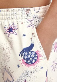 Lichte stoffen shorts met een crèmekleurige achtergrond, versierd met kleurrijke ster- en handpatronen, een elastische tailleband en zijzakken.