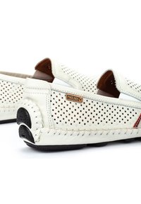 Hvide perforerede læderslippers med brune detaljer og strukturerede gummisåler. Har flettede syninger og et mærketag.
