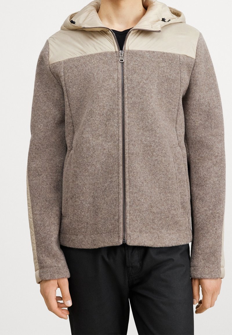 Giacca in misto lana marrone con spalle e cappuccio beige. Chiusura con zip e tasche laterali. Tessuto morbido e pannelli a contrasto. Vestibilità casual.