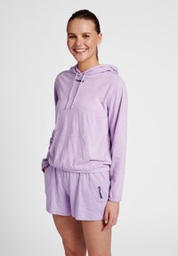 Ljuslila hoodie med känguruficka och logotyp, tillsammans med matchande lila shorts med elastisk midja och logotypdetalj.