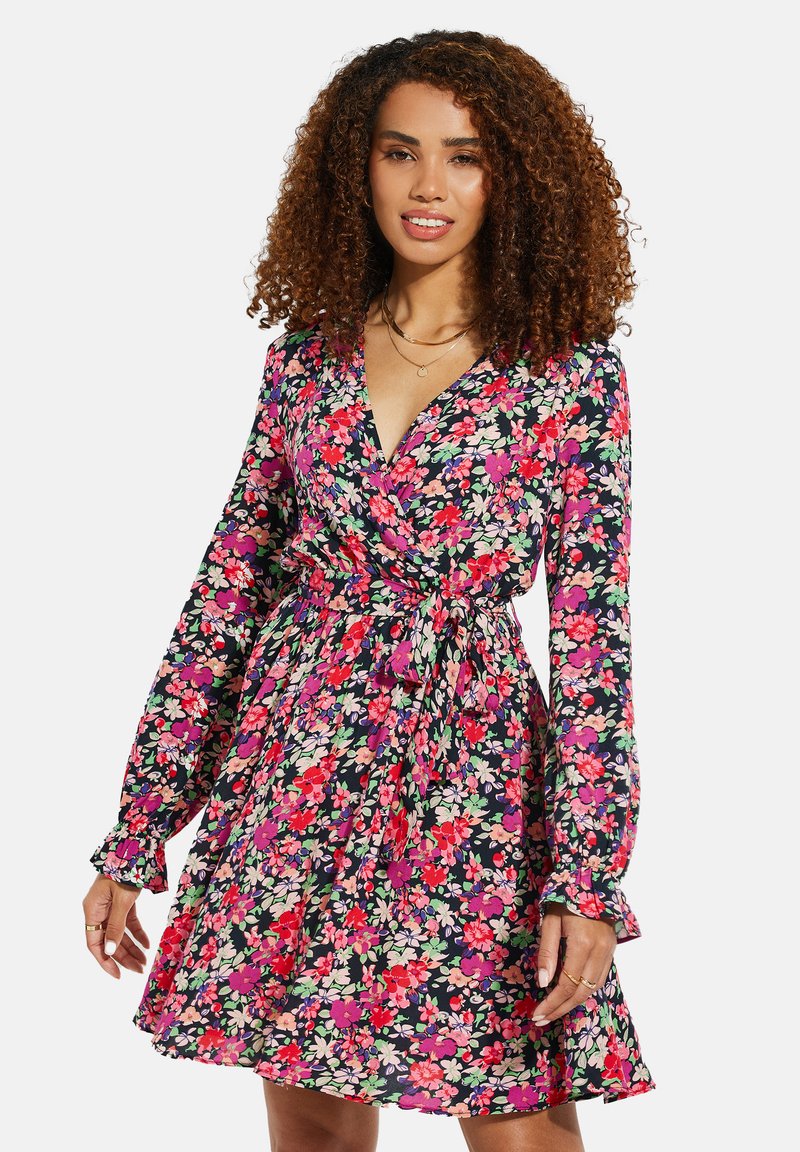 Blumenkleid in Marineblau mit leuchtend pinken und grünen Blumen, langen Ärmeln, gerafften Manschetten und einer taillierten Taille mit Bindeband.