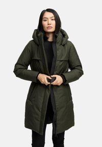 Olivenfarvet lang quiltet frakke med hætte, frontlynlås og knaplukning. Indeholder to brystlommer og struktureret stof.
