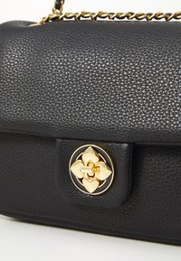 Black leather handbag with a textured finish, featuring a gold hardware clasp with a heart design and a chain strap.