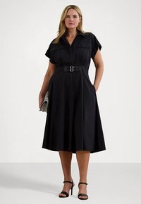 Černé šaty s páskem, krátkými rukávy, áčkovou siluetou, bočními kapsami a plisovanou sukní. Hladká látka v jednobarevném provedení.