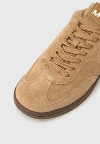 Τακούνι σουέντ σε ταμπά με στρογγυλή μύτη, υφή επιφάνειας και καφέ λαστιχένια σόλα. Διαθέτει πλεκτά κορδόνια και ετικέτα στη γλώσσα με το λογότυπο.