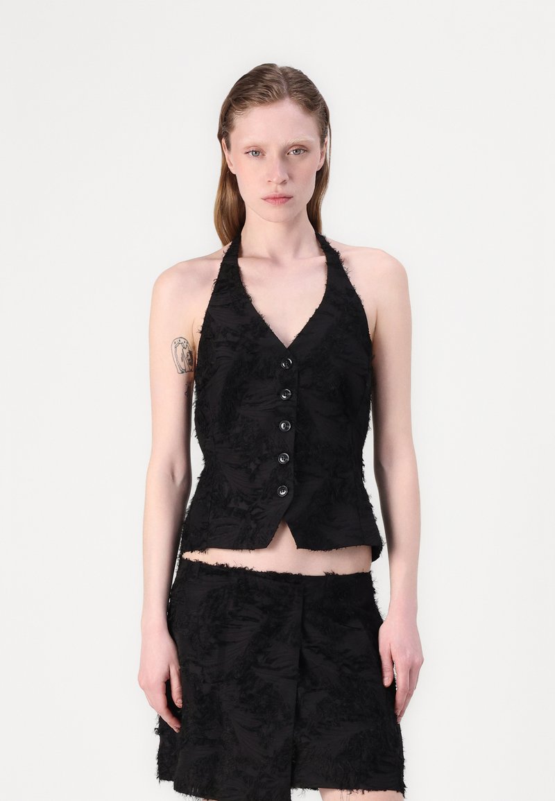 Svart halter-topp med V-hals, laget av teksturert, frynset stoff og seks knapper foran, kombinert med et matchende frynset skjørt.