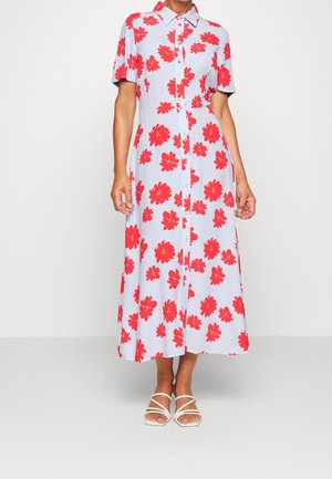 Lyseblå midi-kjole med korte ærmer, rødt blomstermønster, knapper foran og hvide sandaler med remme på en neutral baggrund.