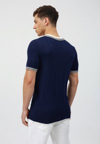 Marineblaues kurzärmeliges Strickhemd mit vertikaler Rippstruktur und weißen Streifen am Kragen und Saum.
