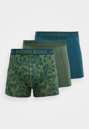 Trois paires de boxers pour hommes : une avec un motif de feuilles vertes, une en vert olive uni, et une en bleu sarcelle foncé. Toutes comportent une ceinture élastique noire.