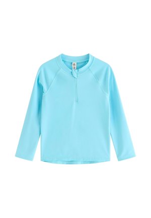 Lyseblå skjorte med lange ærmer, kort lynlås foran og rund halsudskæring, vist på hvid baggrund.