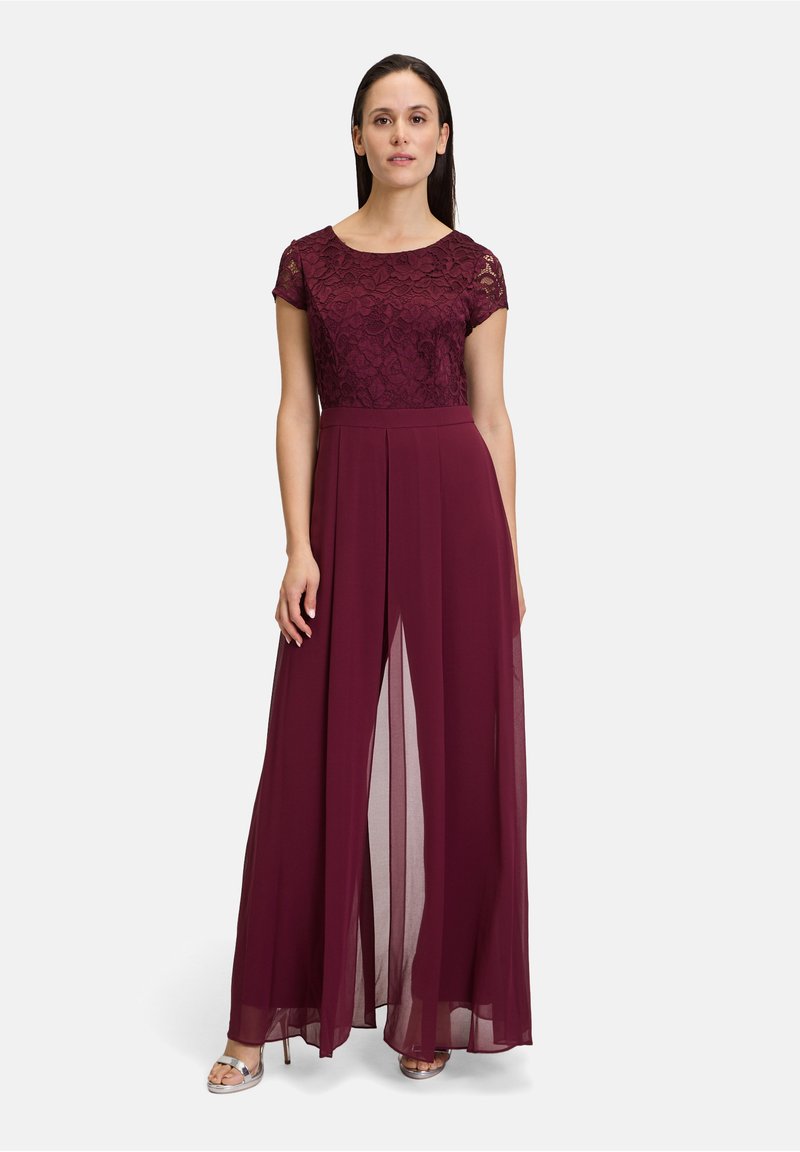 Bordeauxfarbenes Kleid mit Spitzenoberteil, kurzen Ärmeln und plissierten Chiffonrock mit einem Schlitz vorne. Silbersandalen ergänzen das Outfit.
