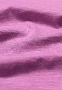 Měkká texturovaná tkanina v světle růžové barvě, s jemným vzorováním a něžnými záhyby, naznačující lehký a hladký materiál.