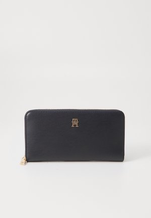 Black leather wallet with a smooth texture and gold hardware. Features a logo accent and a zip closure. Rectangular shape, compact design.